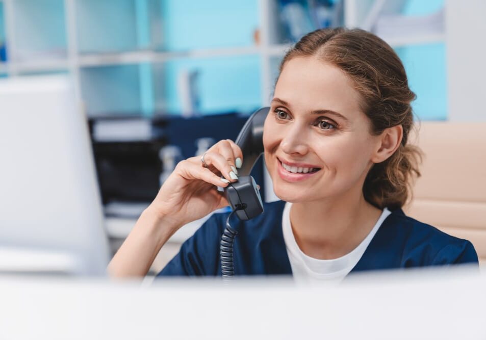 Young,Female,Doctor,Practitioner,Working,At,Reception,Desk,While,Answering